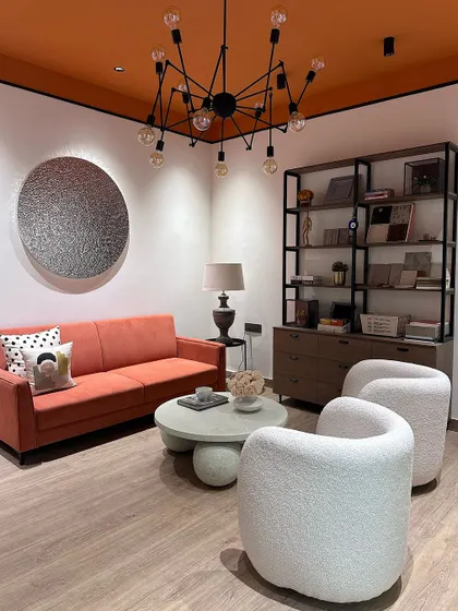 Another corner of our studio, where we showcase material samples and design books. The space features a custom orange sofa and white boucle chairs.