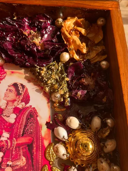 A close-up detail of a teakwood frame, showing preserved kaleera and varmala flowers. The combination of textures and colors is simply breathtaking.