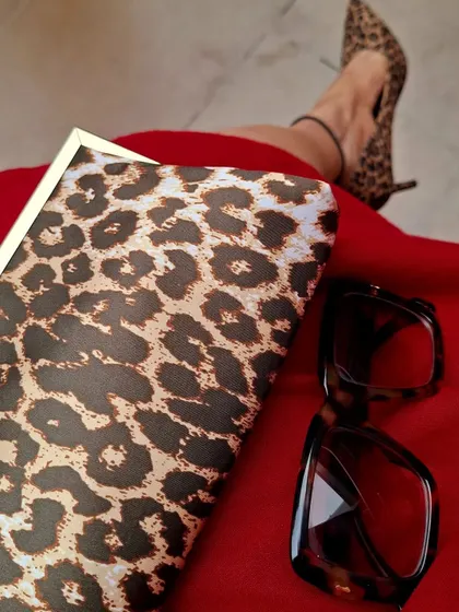 Embrace your wild side. A close-up on leopard print accessories, a classic clutch and pointed-toe heels, paired with a bold red dress. This timeless print adds a touch of fierceness to any outfit.