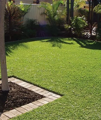 A perfectly manicured lawn with a brick border around a central tree. This detail-oriented approach to edging and borders gives the garden a clean, professional finish.