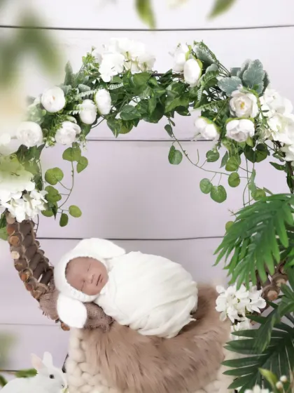 Dressed as a little bunny, this newborn sleeps soundly in our floral wreath prop. This image showcases our creative costumes and setups for themed newborn photography.