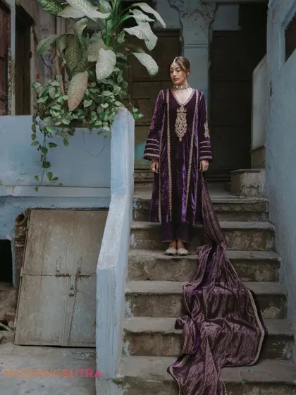 A full-length bridal portrait showcasing the flow and elegance of her outfit against the rustic backdrop of Old Delhi. This shot combines fashion with a sense of place.