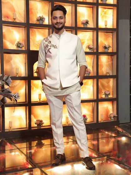 Clean, crisp, and effortlessly elegant. This custom-made Indowestern set features a white bandhgala jacket with delicate floral embroidery on the shoulder, paired with a contrasting inner kurta and tailored trousers.