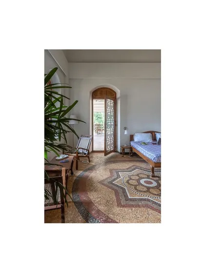 This bedroom view highlights the seamless integration of restored flooring, salvaged wood furniture, and newly designed doors that honor the building's original aesthetic.