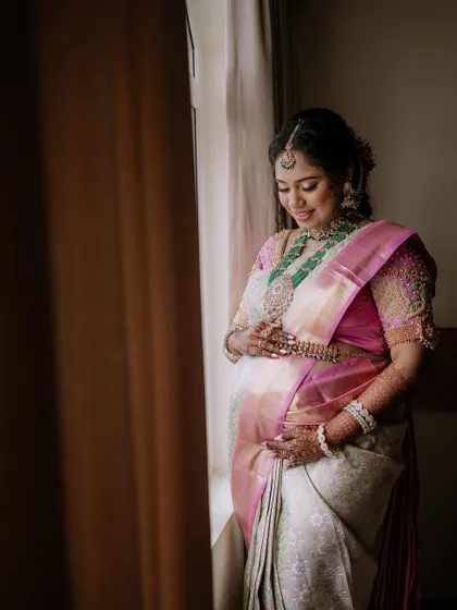 A candid moment during a traditional maternity shoot. The mother-to-be is captured in soft window light, her expression full of warmth and happiness as she looks down, creating a beautiful and natural portrait.