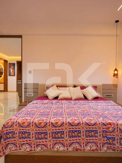 A bedroom that combines a concrete-finish accent wall with a traditional patterned bedspread. The mix of modern and classic elements creates a unique and eclectic style.