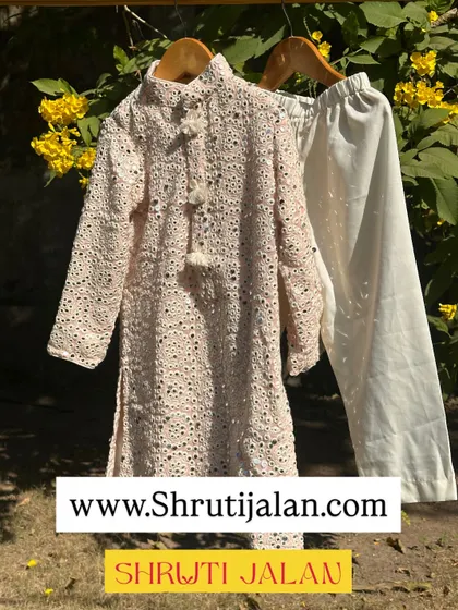 This elegant off-white kurta set features intricate chikankari-style embroidery. It’s a timeless piece that is perfect for any special occasion, from weddings to pujas.