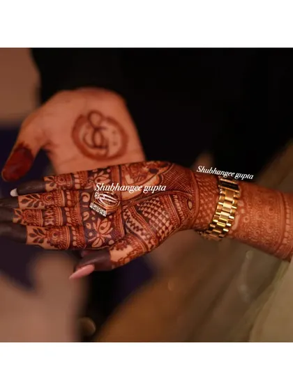 A beautiful photo showing both the bride's and groom's henna stains. The bride's intricate design and the groom's simple symbol both have a lovely, rich color.