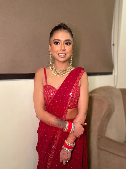 A full shot of the classic red saree and smokey eye combination. The makeup is designed to be bold and make a statement.