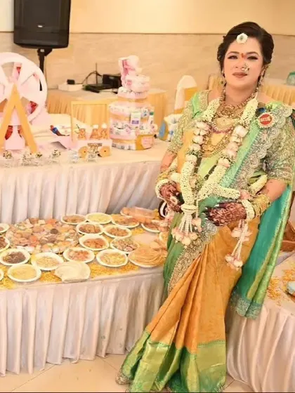 A beautiful mom-to-be posing proudly next to the extensive food and dessert table we created for her baby shower.