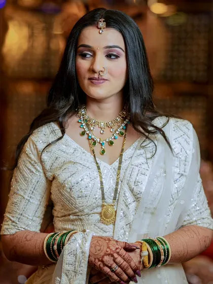 A portrait of a bride in a stunning white sequined outfit, her hands adorned with traditional green bangles and mehndi.