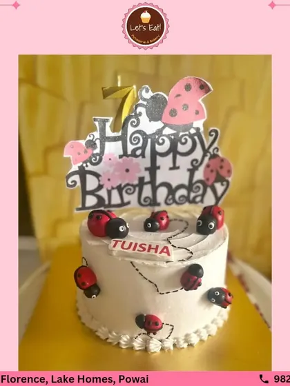 A sweet and simple ladybug-themed birthday cake. The white frosted cake is adorned with cute, handcrafted fondant ladybugs, perfect for a charming and whimsical celebration.
