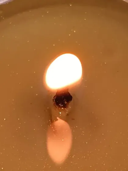 A macro shot of a burning tealight, capturing the beautiful shimmer from the mica mixed into the wax pool.