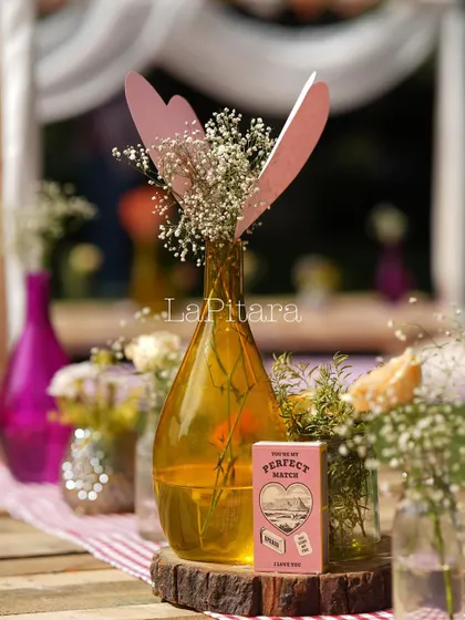A charming table centerpiece with a custom 'Perfect Match' matchbox prop, colorful vases, and fresh flowers.