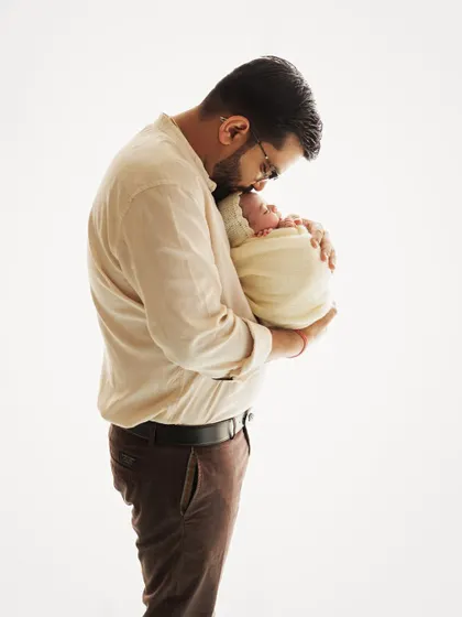 A father's love. This tender portrait shows a dad holding his swaddled newborn close, a quiet and powerful moment captured in a minimalist style.