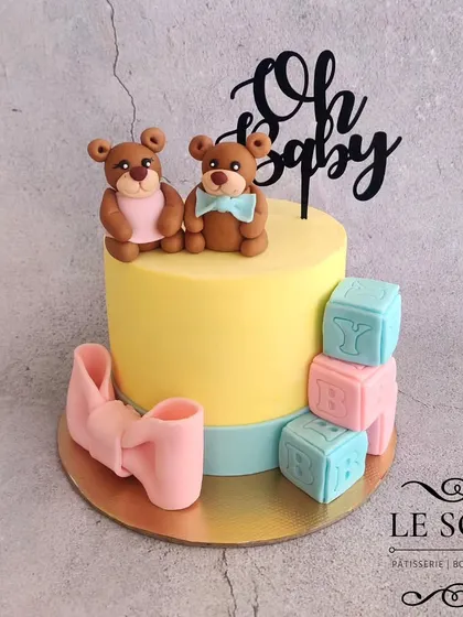 This "Oh Baby" teddy bear cake was for a baby shower. The 1 kg Vanilla Caramel cake is decorated with adorable, hand-sculpted fondant teddy bears, baby blocks, and a large pink bow.