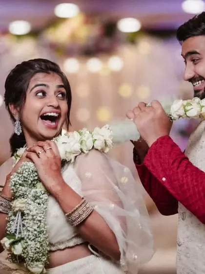 A candid and joyful moment from a Varmala ceremony. The couple's playful interaction with the garland and their genuine smiles make this a heartwarming and memorable shot.
