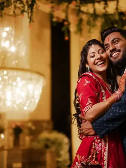 A beautiful, happy portrait of Saurav and Khyati after their Roka ceremony. The warm lighting from the chandelier adds a touch of glamour to their joyful embrace.
