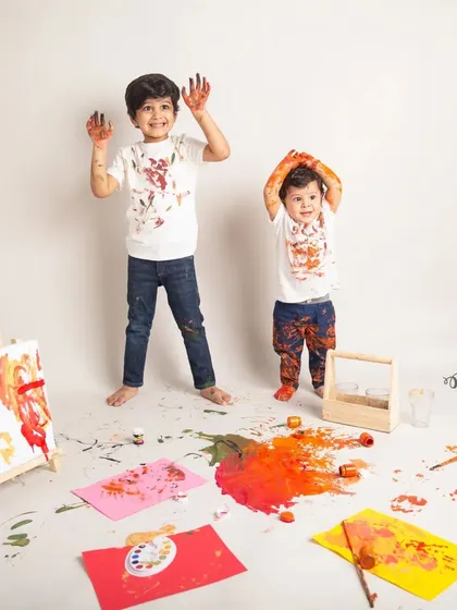 Hands up if you're having fun. The two brothers show off their paint-covered hands during a messy but memorable color splash photoshoot in the studio.