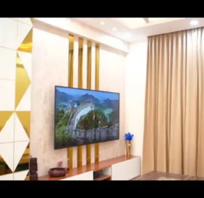 A modern TV wall with a striking geometric pattern of white and gold-mirrored triangles. This feature wall acts as a bold piece of art, elevating the entire living room.