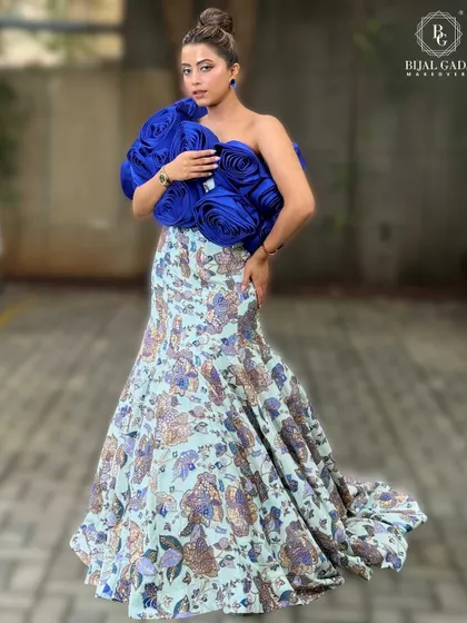 A full-body pose showcasing the entire ensemble. The makeup is designed to complement the unique silhouette and colors of the dress.