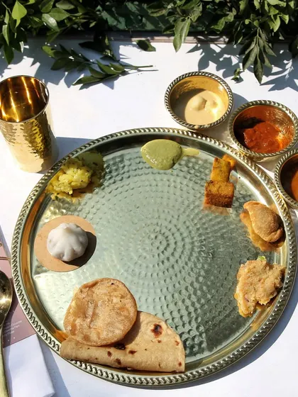 An elegant, modern take on the Pangat thali. The traditional food is served on stylish hammered metal plates, blending tradition with contemporary aesthetics.