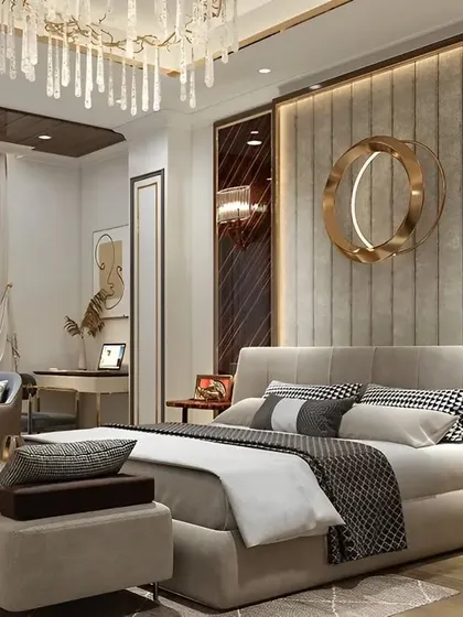 A luxurious bedroom design featuring a floor-to-ceiling upholstered headboard with brass accents. The room includes a comfortable seating area and a dedicated workspace, blending comfort with functionality.