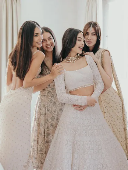 The bride, Julia, sharing a happy moment with her bridesmaids in London. The soft, natural light from the window creates a beautiful, gentle mood.