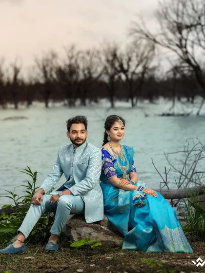 A classic portrait of a couple by the lake, showcasing their elegant traditional attire against a moody, natural backdrop.