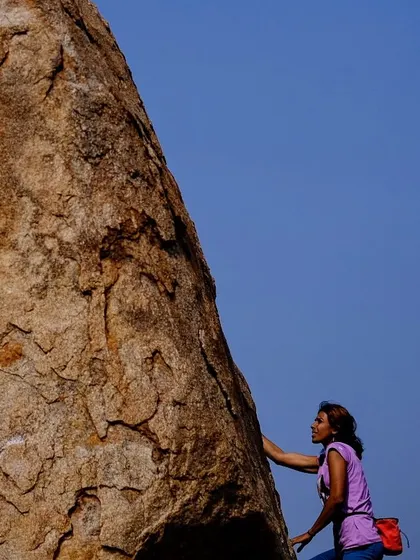 A climber studies the rock face in Hampi, planning her next move. Bouldering is as much a mental puzzle as it is a physical challenge, and we love solving these problems together.