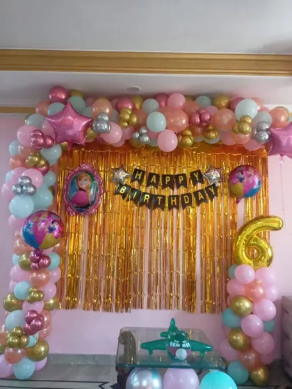 A simple and sweet birthday setup at home, with a pink and gold balloon arch over a shimmer backdrop.