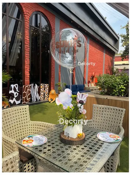 An outdoor table setting for a jungle party, with a custom balloon and themed centerpiece.