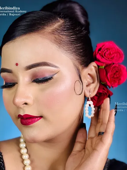 A classic retro look featuring a sleek, side-parted bun adorned with red roses, paired with winged eyeliner.