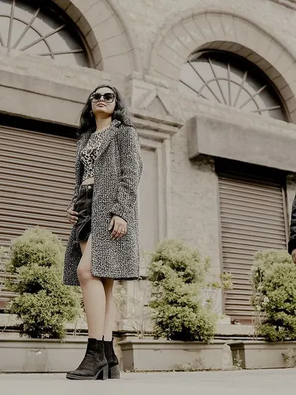 A low-angle, wide shot of a couple posing in front of a stone building, giving a powerful and fashionable look.