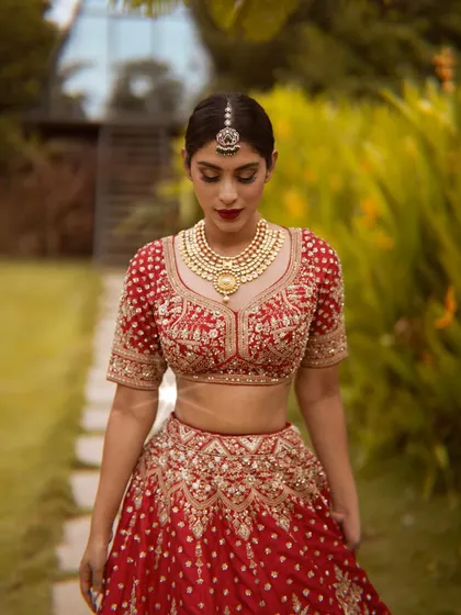 This is a modern take on a classic bridal look. The rich red lehenga is complemented by a bold red lip and defined eyes, creating a regal and timeless aesthetic for any bride's special day.