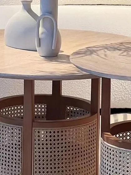 A detailed shot of the Siena Coffee and End Tables, highlighting the intricate rattan weaving on the base and the smooth travertine top. This is where craftsmanship and natural beauty meet.