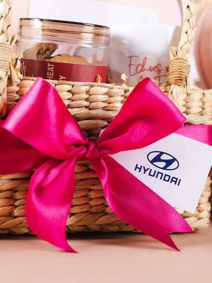 A close-up of the custom-branded tag and vibrant pink ribbon on the Hyundai Women's Day basket. These details tie the whole look together.