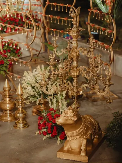A collection of traditional brass decor, including a Nandi statue and ornate multi-tiered lamps (deepams). These elements were placed around the mandap to enhance the authentic, regal, and spiritual feel of the ceremony.