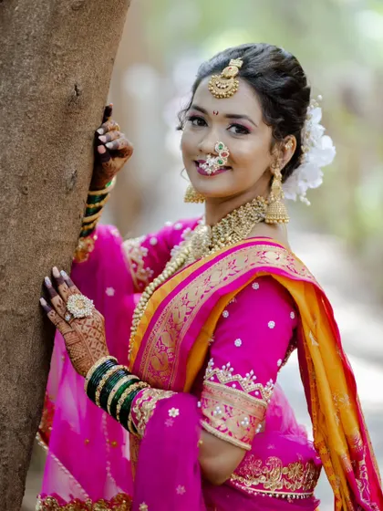 A beautiful outdoor portrait of our Maharashtrian bride. The natural light highlights the flawless finish of her makeup and the rich colors of her yellow and pink saree.