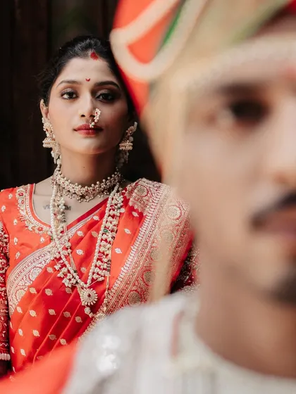 An artistic portrait focusing on the bride's regal expression, with the groom's face softly blurred in the foreground.