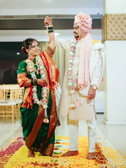 A celebratory moment as the couple completes a ritual on a path of flowers, their hands raised in triumph.