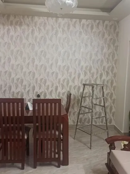 A dining area with a light grey wallpaper featuring a subtle leaf pattern. The design adds texture and elegance, making the space feel more refined.