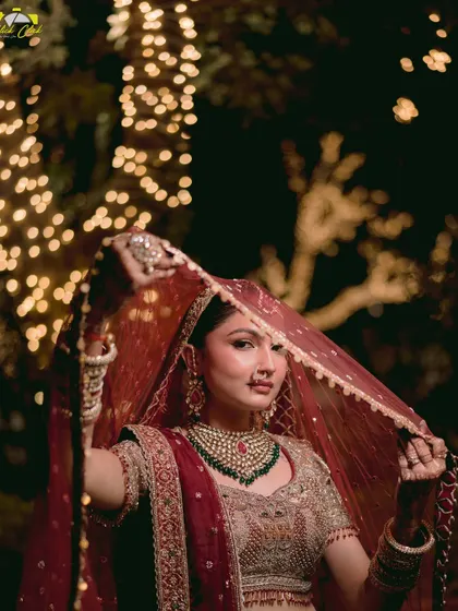 The bride lifts her veil, giving a glimpse of her beautiful smile. This classic pose is captured with a modern, artistic eye, making it a timeless bridal portrait.