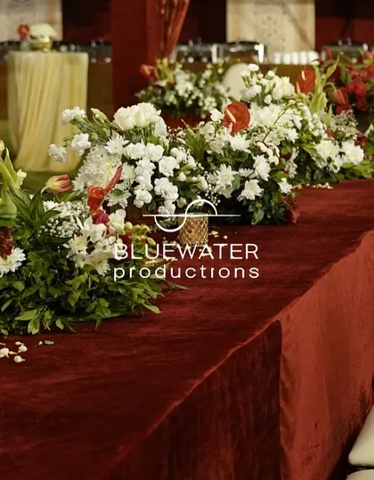 A beautifully set dining table for a traditional wedding, with a rich red velvet runner, ornate chairs, and classic floral arrangements.