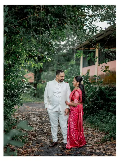 A romantic portrait of an engaged couple in a lush, green setting. The natural canopy of trees creates a beautiful, intimate frame for this engagement photo.