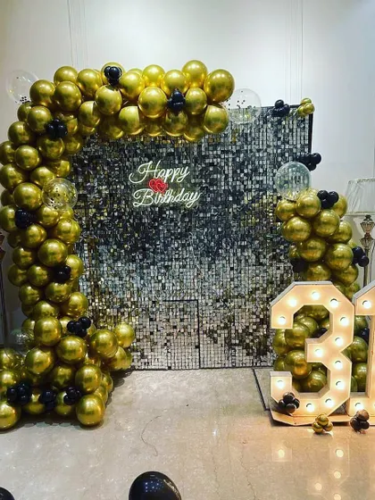 A bold and glamorous 31st birthday setup. The decor features a full arch of gold chrome balloons against a silver shimmer wall, complete with a neon sign and marquee numbers.