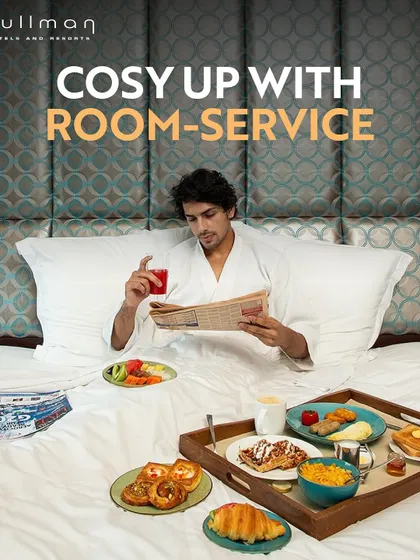 Cozy up with room service at Pullman. This image of a guest enjoying an elaborate breakfast in bed shows the luxurious and comfortable staycation experience I offer.
