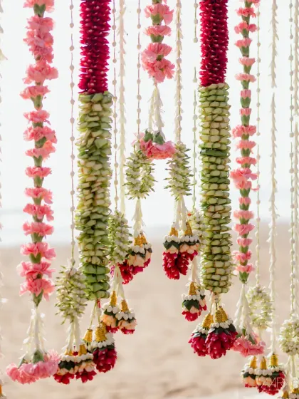 Intricate floral garlands made from carnations and jasmine buds, created for a surreal sunrise wedding by the sea. The craftsmanship in these traditional decorations is simply breathtaking.