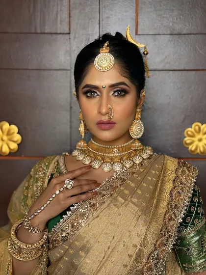 A close-up of a model in a traditional gold-look saree, adorned with heavy temple jewellery, including a statement choker and hathphool.