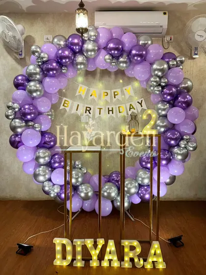 A large balloon ring in purple and silver, with pedestals and marquee letters, creating a grand setup for a 2nd birthday.